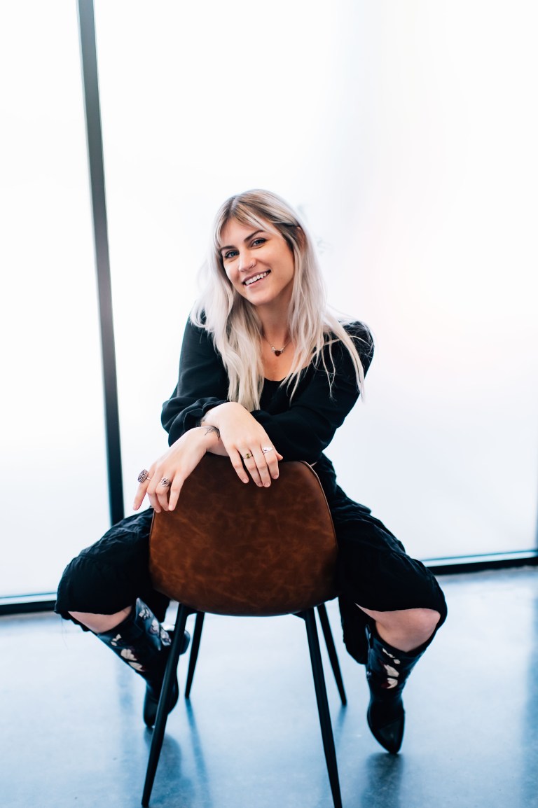 Kenzie, veterinary assistant at Veterinary Vision Specialists, smiling while seated on a chair, showcasing her friendly demeanor and dedication to animal care.