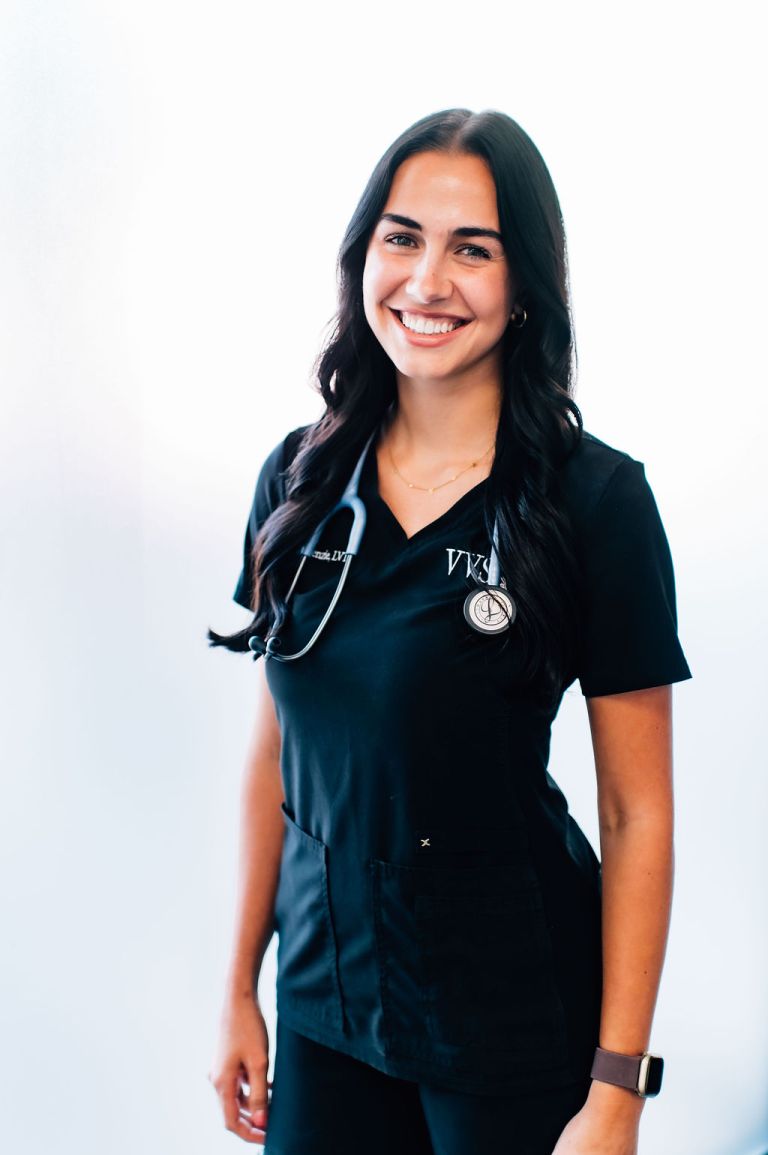 Licensed Veterinary Technician in scrubs with stethoscope, smiling against a light background, representing compassionate care in veterinary ophthalmology at Veterinary Vision Specialists.